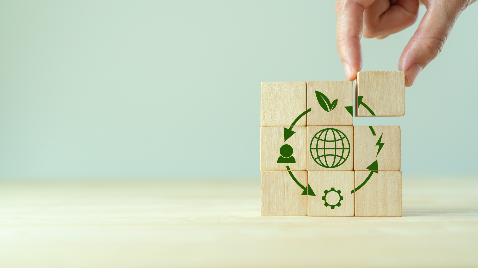 dłoń układa klocki z motywem recyklingu i obiegu zamkniętego
